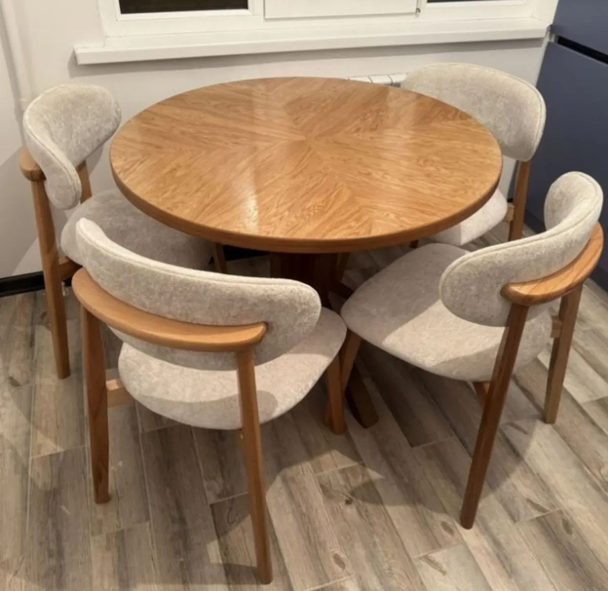 Round wooden dining table with upholstered chairs by Kabom Furniture